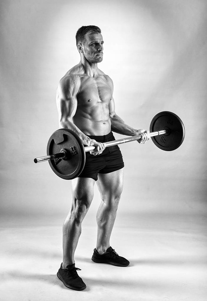 Man doing biceps curl with barbell in studio - Foto, immagini