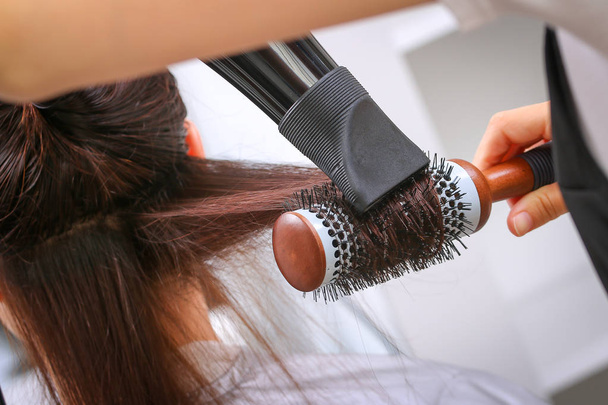 Dívka v salonu krásy, zatímco kadeřnice vlasy suché vlasy - Fotografie, Obrázek