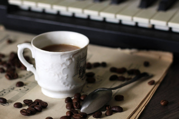 eine Tasse heißen Kaffee, Noten und ein Klavier. - Foto, Bild