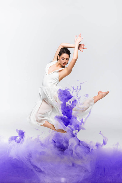 bella ballerina in abito bianco ballare vicino spruzzi di vernice blu sul fondo grigio
 - Foto, immagini
