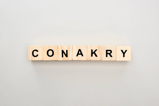 top view of wooden blocks with Conakry lettering on grey background - 写真・画像