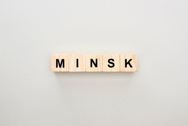 top view of wooden blocks with Minsk lettering on grey background - Fotó, kép