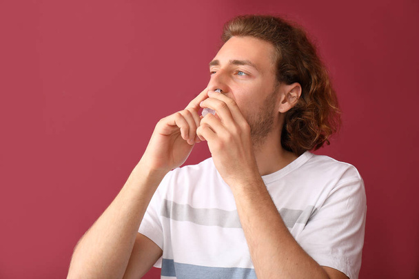 Hombre joven con gotas nasales sobre fondo de color
 - Foto, imagen