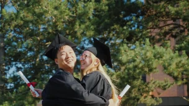 Los graduados se felicitan mutuamente por graduarse de la universidad, abrazándose
 - Metraje, vídeo