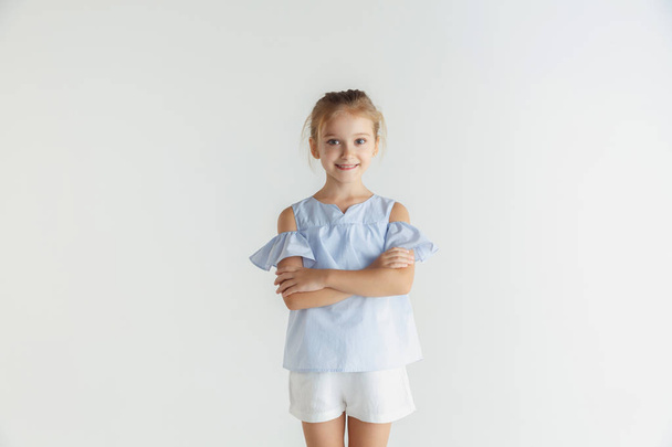 Little smiling girl posing in casual clothes on white studio background - Foto, imagen