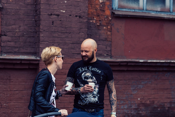 Belarus, Minsk, may 17, 2015, Oktyabrskaya street, biker festival. couple of bikers drinking coffee near the city building. - Fotoğraf, Görsel