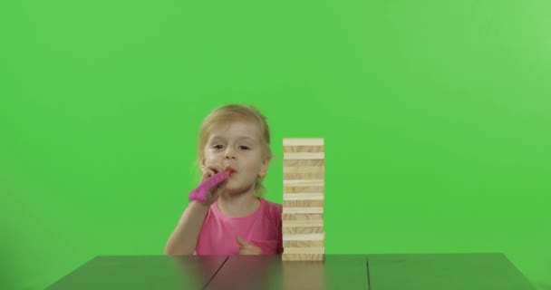 Το παιδί παίζει Τζένγκα. Το κοριτσάκι τραβάει ξύλινα τετράγωνα από έναν πύργο - Πλάνα, βίντεο