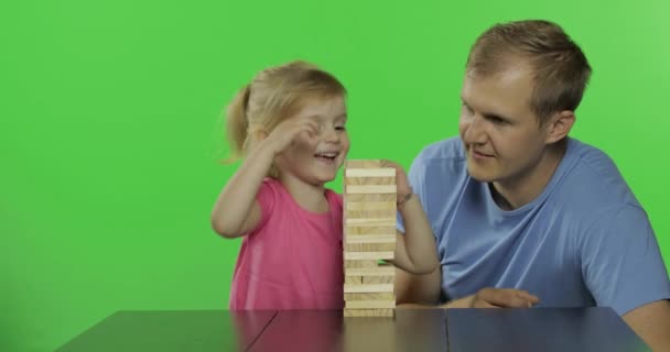 Father and daughter plays the jenga. Little child pulls wooden blocks from tower - Footage, Video