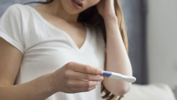 Обрезанное изображение разочарованной женщины, проходящей тест на беременность
 - Фото, изображение