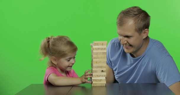 Father and daughter plays the jenga. Little child pulls wooden blocks from tower - Footage, Video