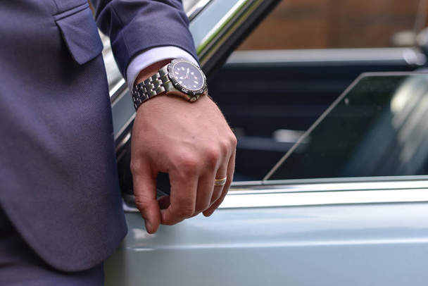 бізнесмен з наручним годинником біля автомобіля
 - Фото, зображення