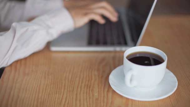 περικομμένη θέα της αφρικανικής αμερικανικής επιχειρηματία με χρήση φορητού υπολογιστή κοντά στο φλιτζάνι του καφέ - Πλάνα, βίντεο