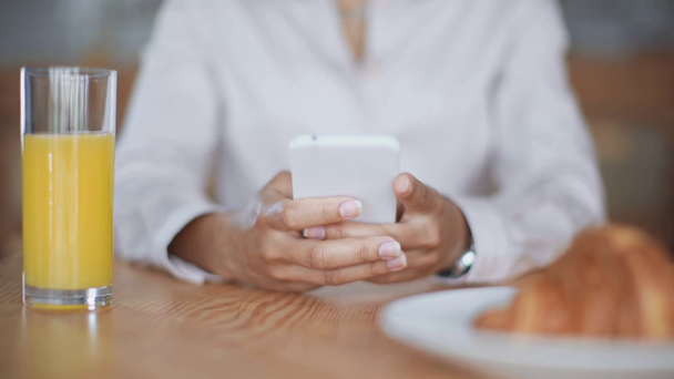 vista recortada de la mujer de negocios afroamericana usando teléfono inteligente en la cafetería
 - Imágenes, Vídeo