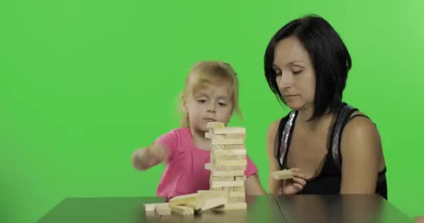 母と娘はジェンガを演じます。木製のブロックから塔を作る子供 - 映像、動画