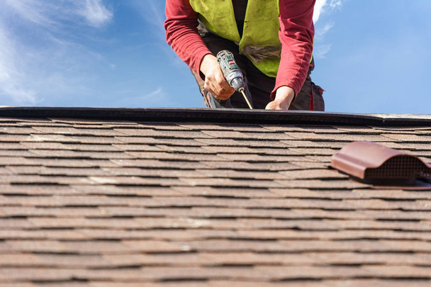 Workman install element of tile roof on new home under construction - 写真・画像