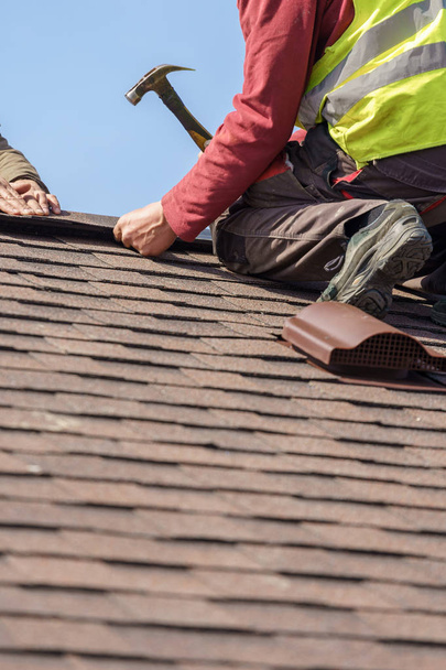 作業員は、建設中の新しい家にタイル屋根の要素をインストールします - 写真・画像