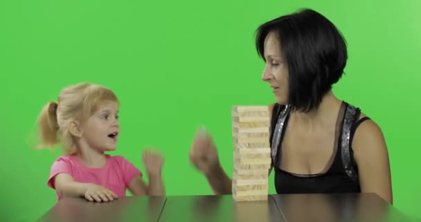 Moeder en dochter spelen de Jenga. Kind trekt houten blokken van de toren - Video