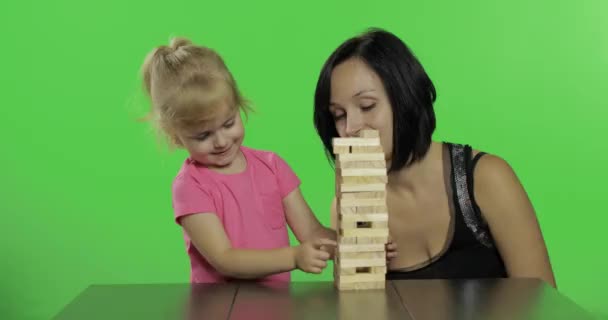 Anne ve kızı jenga oynar. Çocuk kuleden ahşap bloklar çeker - Video, Çekim