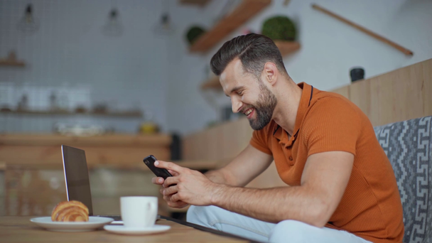 uomo d'affari informale che utilizza smartphone a tavola con laptop, caffè e croissant nel caffè
 - Filmati, video