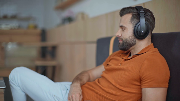 příležitostný obchodník s naslouchající hudbou ve sluchátkách v kavárně - Záběry, video