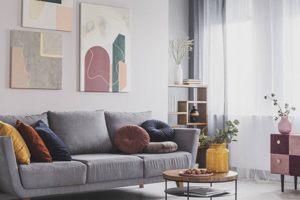 Coffee table in front of grey couch in scandinavian living room - Fotó, kép