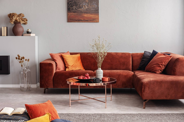 Fashionable velvet corner sofa with pillows next to elegant coffee table with flowers - Φωτογραφία, εικόνα