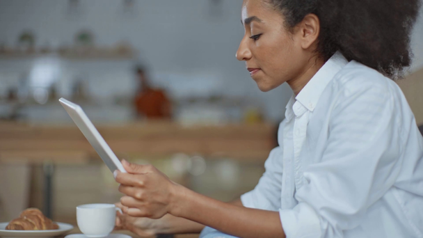 afro-americana donna d'affari utilizzando tablet digitale e bere caffè in caffè
 - Filmati, video