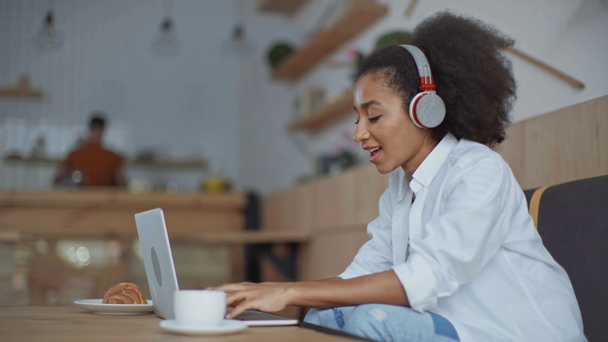 femme d'affaires afro-américaine dans les écouteurs à l'aide d'un ordinateur portable dans le café
 - Séquence, vidéo