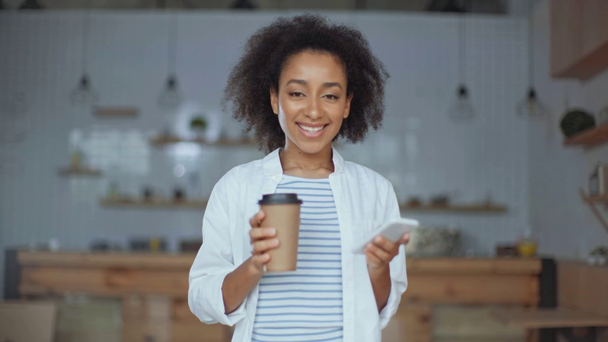 Afro-Amerikaanse vrouw met behulp van smartphone, koffie drinken in café - Video