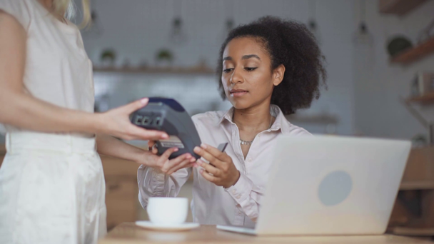 serveuse donnant terminal à une jeune femme d'affaires afro-américaine pour le paiement avec la technologie Paypass dans un café
 - Séquence, vidéo