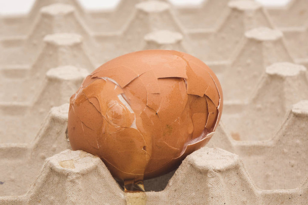 Carton packaging for eggs with broken eggshell on a light background. - 写真・画像