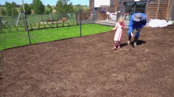 Menina bonito filha ajudar pai pai com gramado grama semeadura semeadura no quintal da casa
. - Filmagem, Vídeo