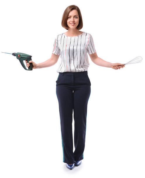 Young businesswoman with electric drill and whisk on white background. Concept of balance - Foto, imagen