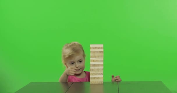 Het kind speelt de Jenga. Klein meisje trekt houten blokken van een toren - Video