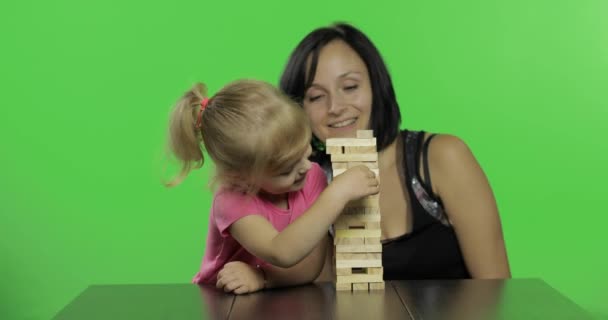 Moeder en dochter spelen de Jenga. Kind trekt houten blokken van de toren - Video