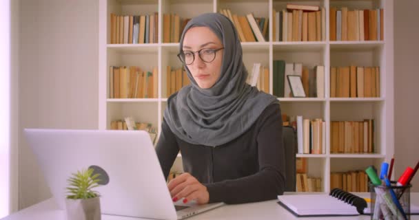 Closeup portrait of young attractive muslim businesswoman in hijab using laptop in library indoors - Filmagem, Vídeo