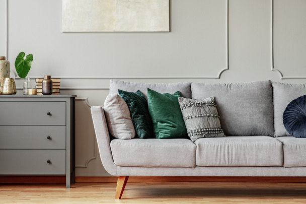Pillows on long comfortable living room couch in grey scandinavian style interior with wooden floor - Foto, Imagem