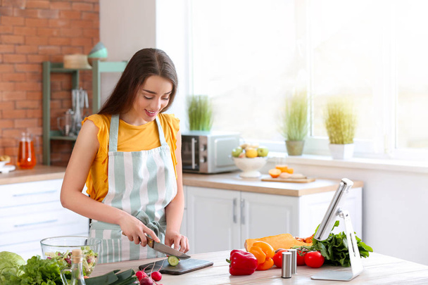 Beautiful woman preparing tasty vegetable salad in kitchen at home - Foto, Imagem