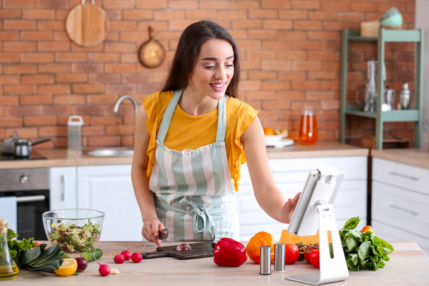 Kaunis nainen valmistelee maukasta kasvissalaattia keittiössä kotona
 - Valokuva, kuva