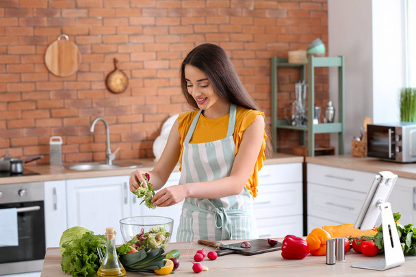 Krásná žena připravuje chutný zeleninový salát v kuchyni doma - Fotografie, Obrázek