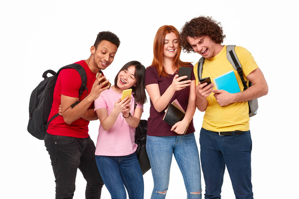 Cheerful multiethnic students sharing smartphones - Foto, imagen