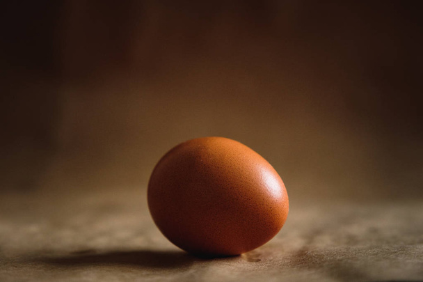 Photo of a brown chicken egg on a brown background - Photo, Image