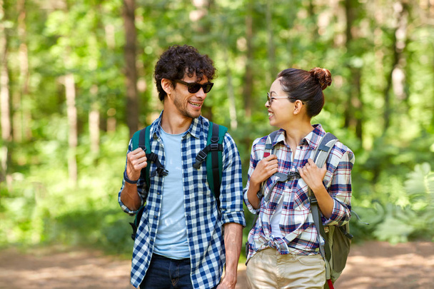 mixed race couple with backpacks hiking in forest - Photo, image