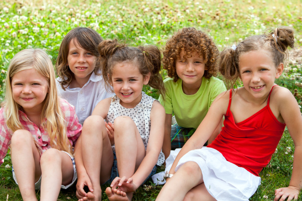 Enfants assis ensemble dans un champ de fleurs
. - Photo, image