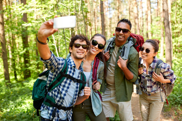 friends with backpacks hiking and taking selfie - Фото, зображення