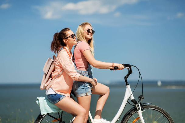 teenage girls or friends riding bicycle in summer - Фото, зображення