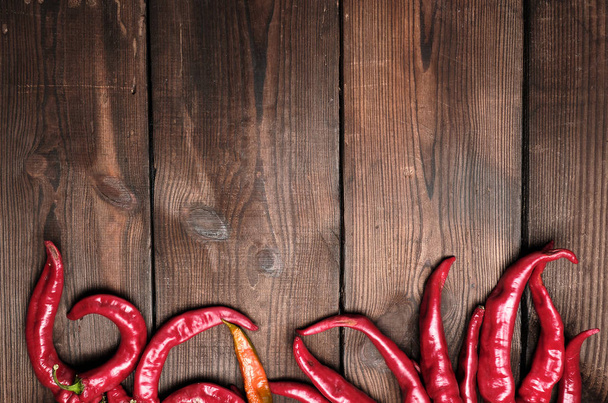 ώριμες κόκκινες πιπεριές τσίλι σε ένα καφέ ξύλινο vintage φόντο από - Φωτογραφία, εικόνα