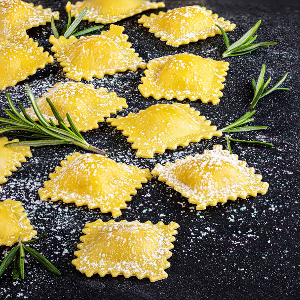 Raviolli with flour and herbs on dark background, top view.  Cop - Photo, image