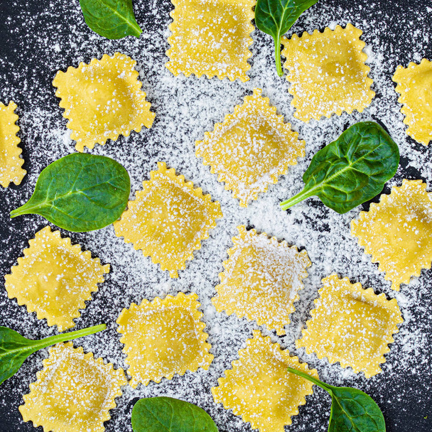 Fresh ravioli pasta with Spinach, flour and herbs on dark backgr - Photo, image
