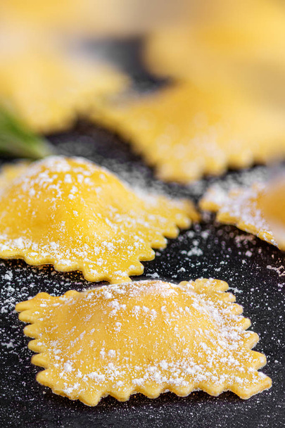 Raviolli met meel en kruiden op zwarte achtergrond, close-up. Het - Foto, afbeelding